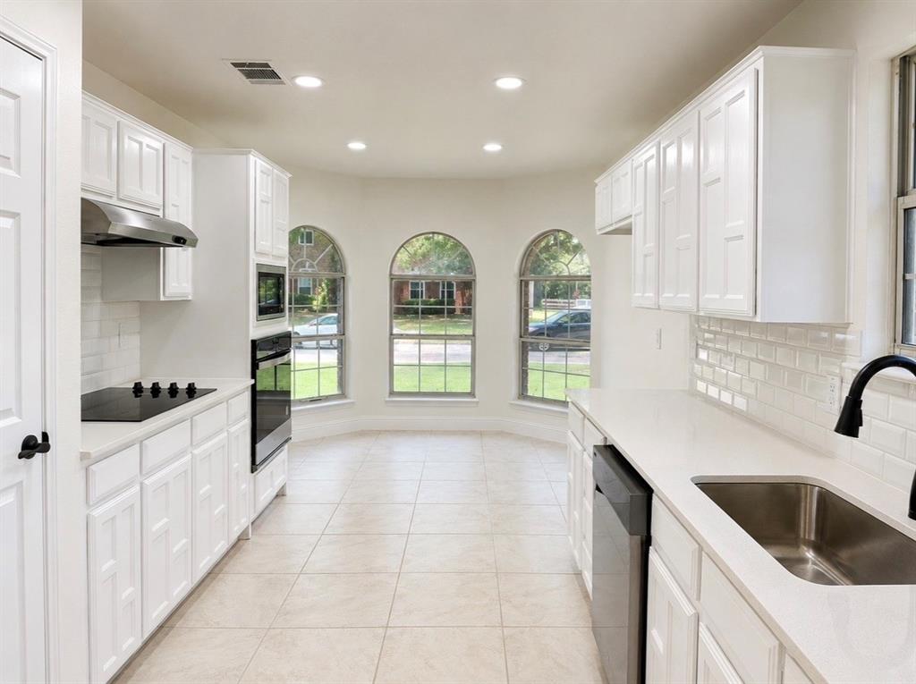Kitchen featuring white cabinetry, subway tile backsplash, solid-surface countertops, stainless steel appliances, and arched windows