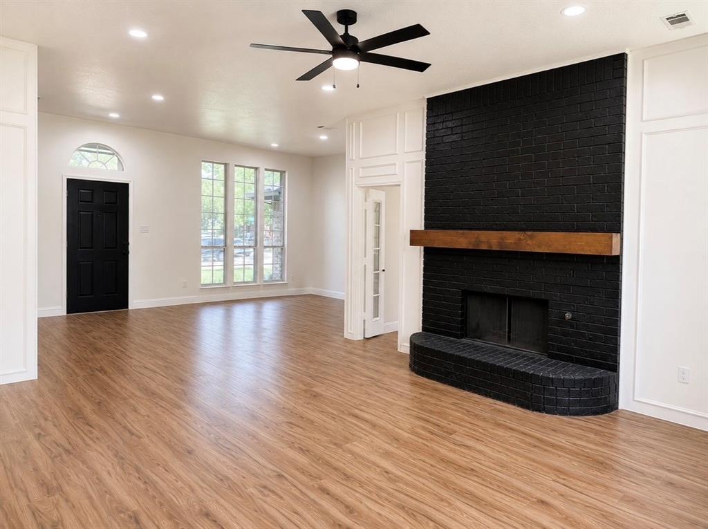 Floor-to-ceiling painted brick fireplace featuring a wood mantel, wood-finish flooring, recessed lighting, multi-pane windows, and a ceiling fan