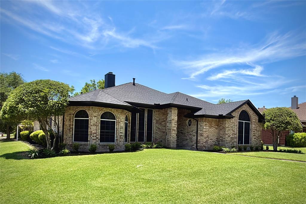 Single-story brick exterior featuring a hip roof, arched windows, and a manicured lawn