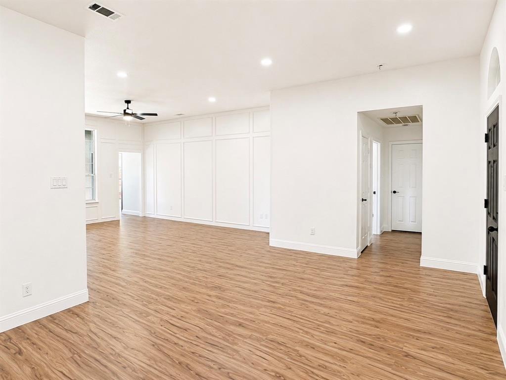 Open-concept interior featuring wood-finish flooring, wainscot wall paneling, recessed lighting, and a ceiling fan