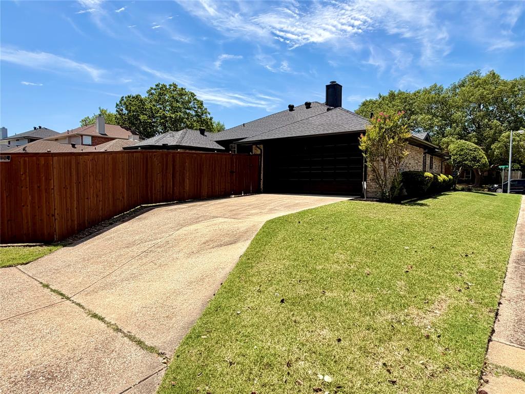 Exterior featuring a brick facade, concrete driveway, attached garage, and vertical wood plank privacy fencing