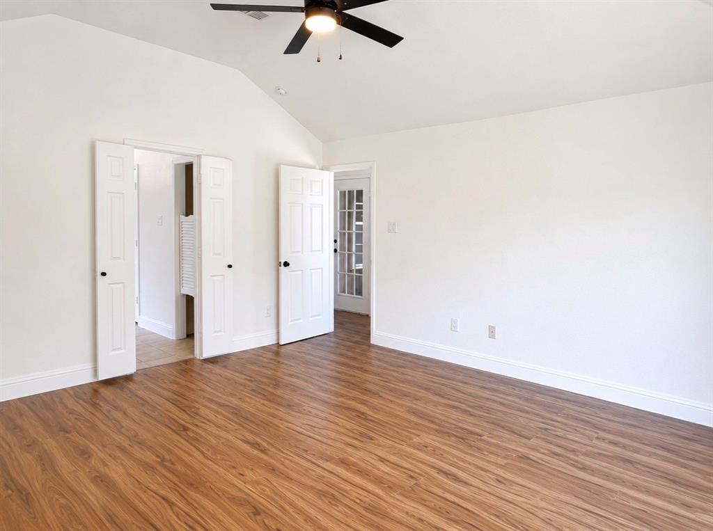 Vaulted ceilings, wood-finish flooring, ceiling fan with integrated lighting, multi-panel interior doors, and a glass-paneled exterior door