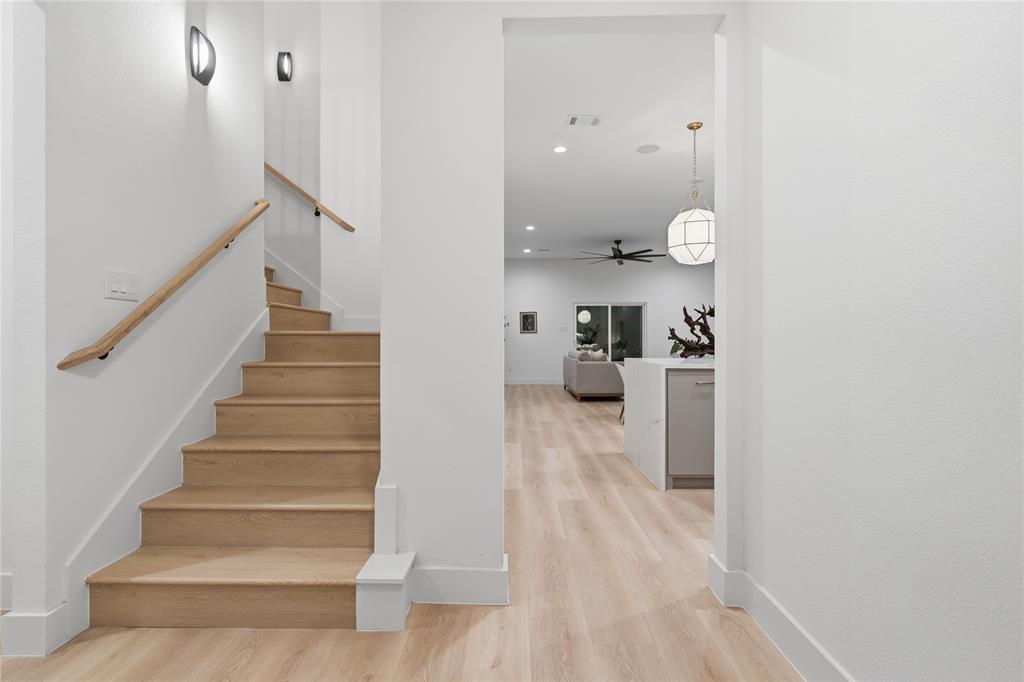 Staircase featuring wood-finish treads and a natural wood handrail, accompanied by wood-finish flooring, recessed lighting, and a geometric pendant fixture Staircase featuring wood-finish treads and a natural wood handrail, accompanied by wood-finish flooring, recessed lighting, and a geometric pendant fixture