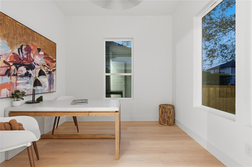 Bright room featuring wood-finish flooring, crisp white walls, and oversized windows providing natural illumination Bright room featuring wood-finish flooring, crisp white walls, and oversized windows providing natural illumination