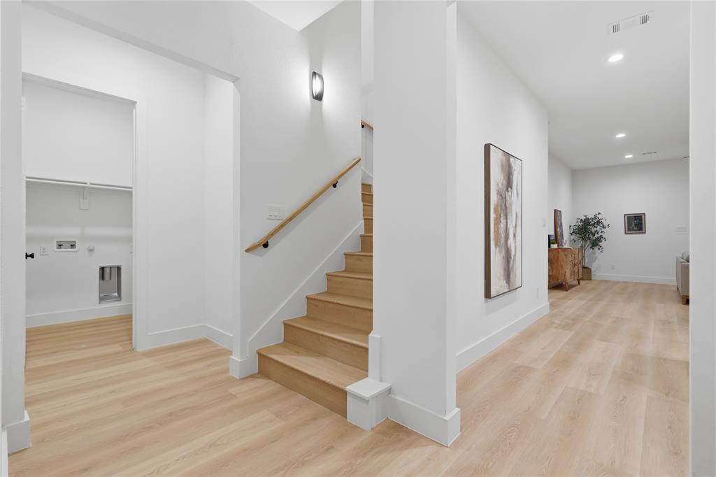 Interior featuring wood-finish flooring, staircase with a wood handrail, recessed lighting, and a utility space with plumbing connections Interior featuring wood-finish flooring, staircase with a wood handrail, recessed lighting, and a utility space with plumbing connections