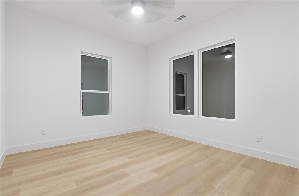 Interior space featuring wood-finish flooring, white walls, multiple windows, and a ceiling-mounted light fixture