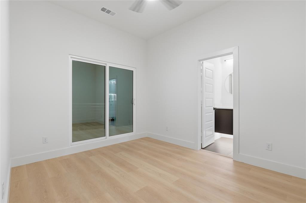 Room featuring wood-finish flooring, high ceilings with a mounted ceiling fan, and sliding glass doors