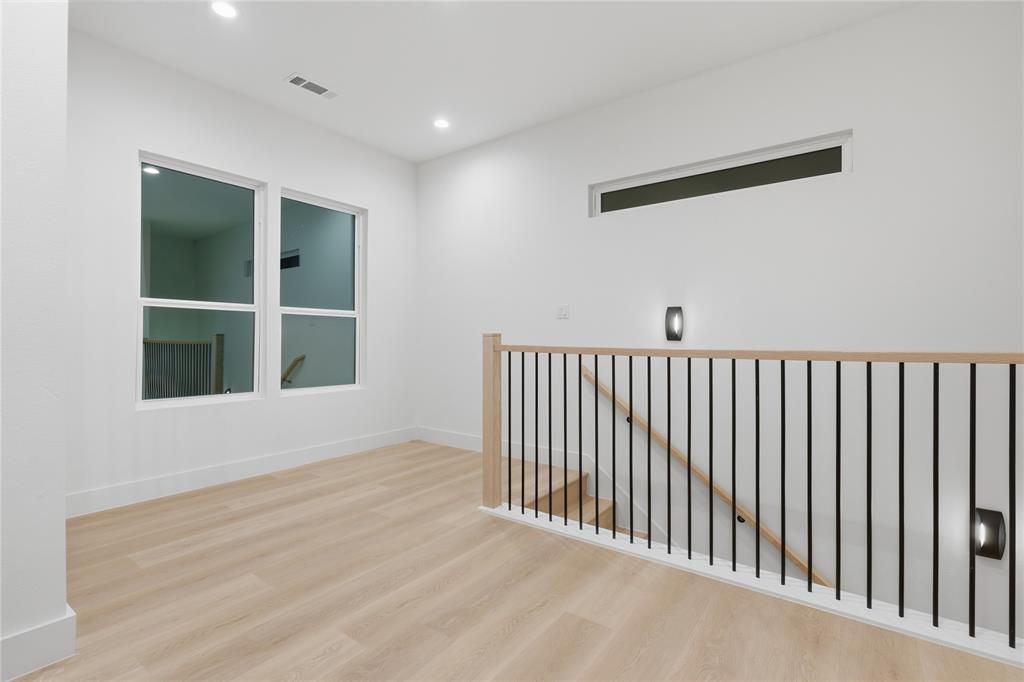 Interior space featuring wood-finish flooring, recessed lighting, a horizontal clerestory window, and a metal balustrade with a wooden handrail