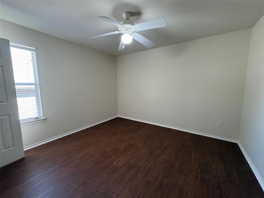 Room featuring wood-finish flooring, a white ceiling fan with integrated lighting, and a single-pane window