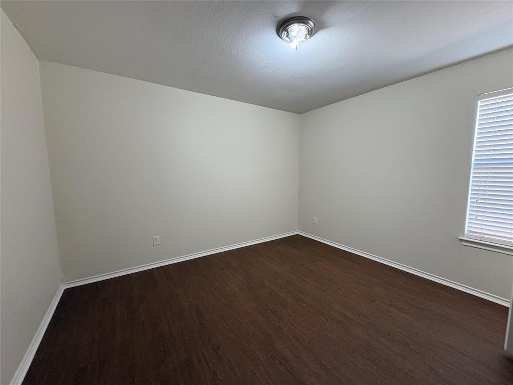 Room featuring neutral wall paint, wood-finish flooring, a flush-mount ceiling light fixture, and horizontal window blinds
