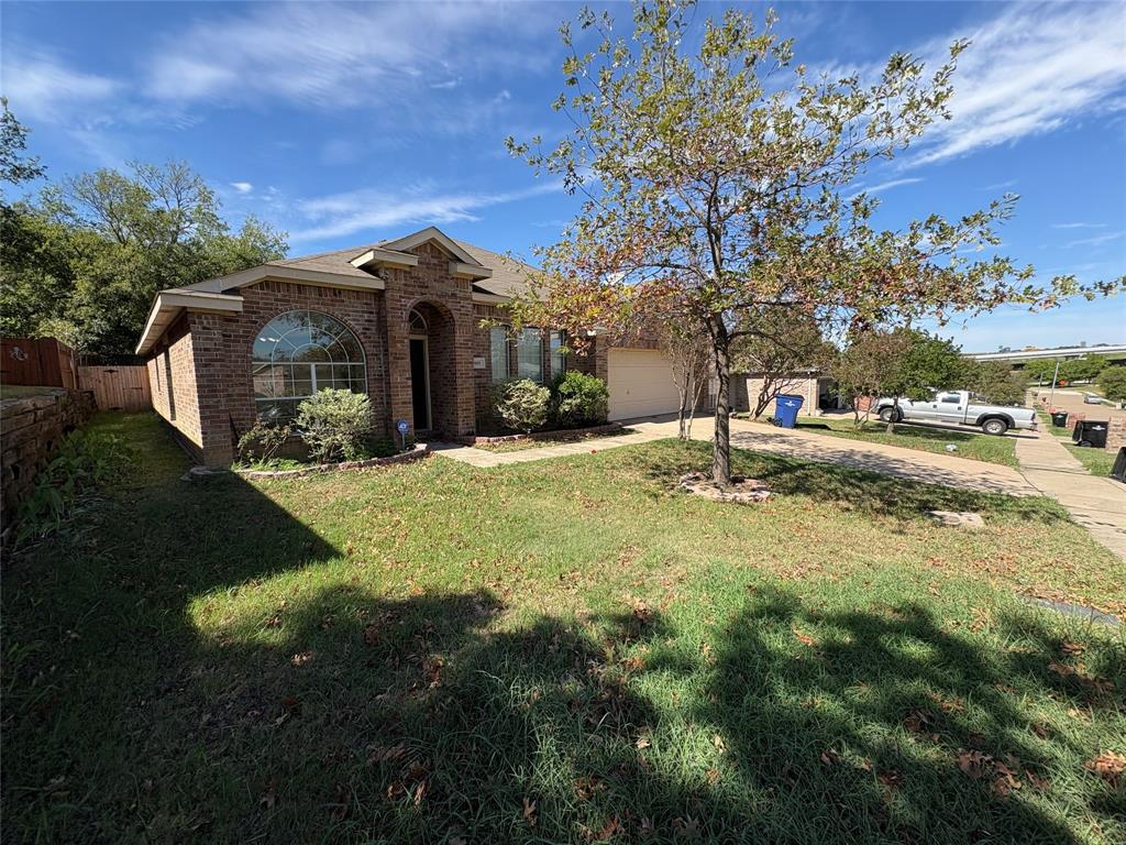 Single-story brick exterior featuring an arched entryway, stone retaining wall, and concrete driveway