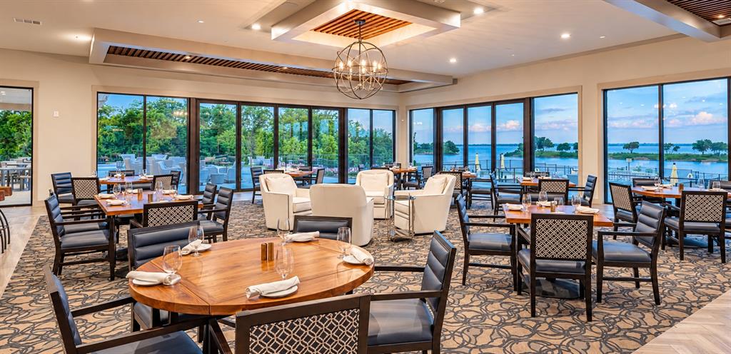 Expansive interior featuring floor-to-ceiling windows, tiered tray ceilings with recessed lighting, an intricate metal globe chandelier, and custom wood-slat ceiling detailing