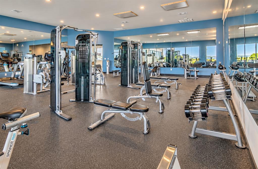 Fitness room featuring recessed lighting, wall-to-wall mirrors, and durable rubber flooring