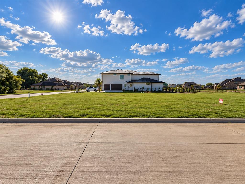 Two-story residence featuring a metal roof, light-toned exterior finish, attached multi-car garage, and expansive open lawn