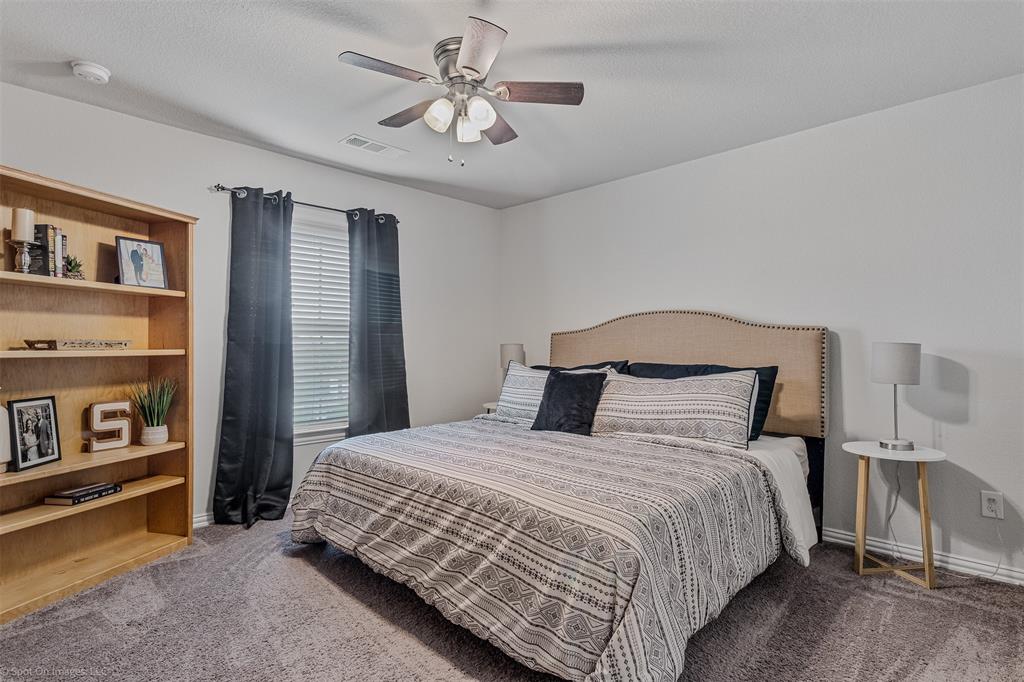 Carpeted bedroom featuring ceiling fan and baseboards