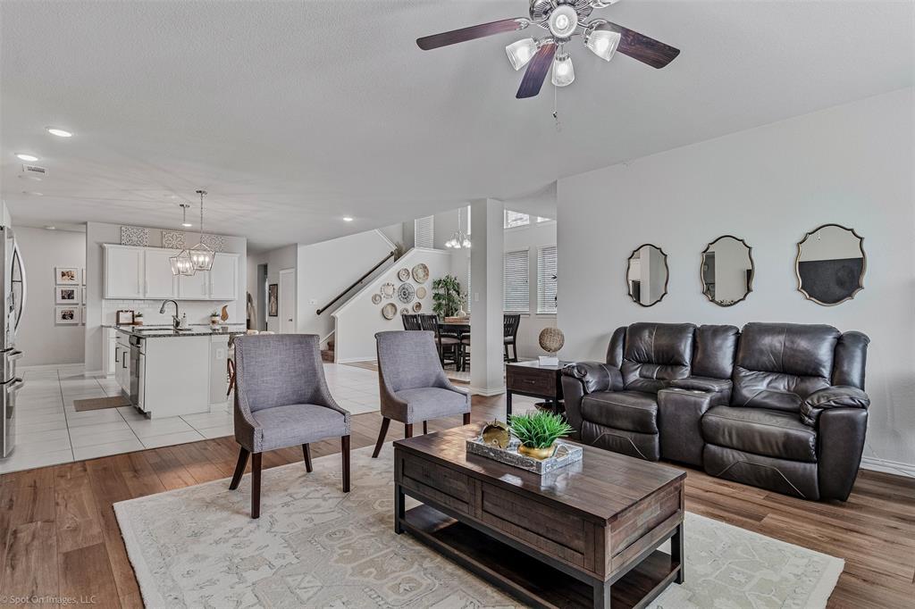 Living room featuring stairway, ceiling fan, a chandelier, light wood-style floors, and recessed lighting Living room featuring stairway, ceiling fan, a chandelier, light wood-style floors, and recessed lighting