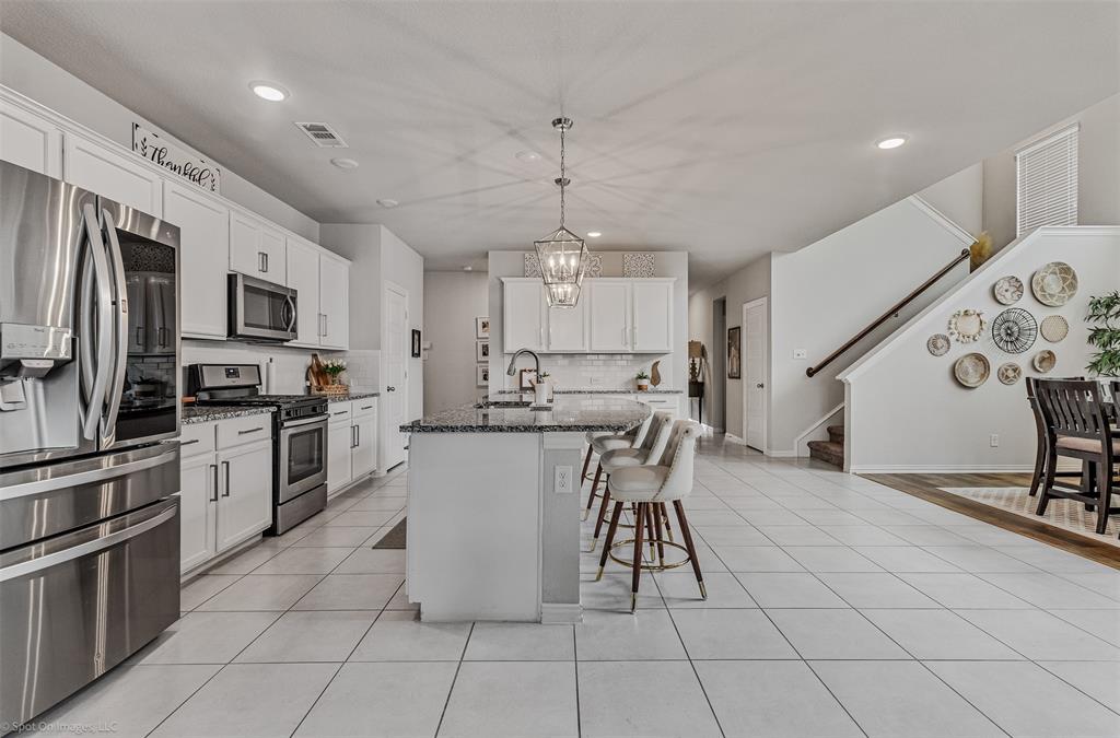 Kitchen with stainless steel appliances, a kitchen breakfast bar, recessed lighting, decorative backsplash, and dark stone counters Kitchen with stainless steel appliances, a kitchen breakfast bar, recessed lighting, decorative backsplash, and dark stone counters