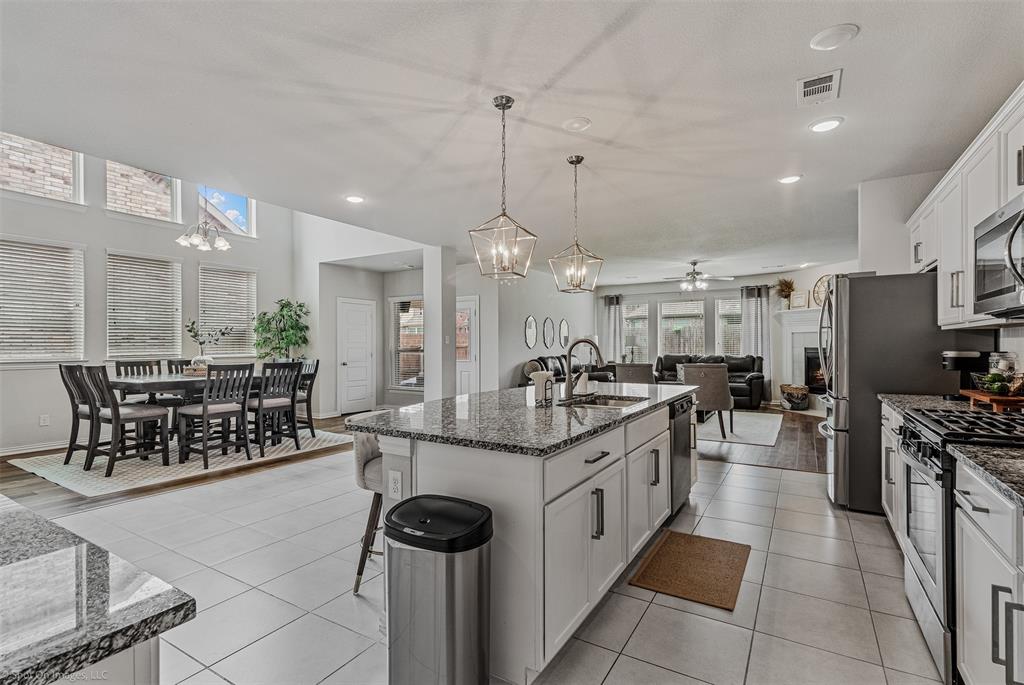 Kitchen with appliances with stainless steel finishes, a chandelier, open floor plan, dark stone counters, and a center island with sink