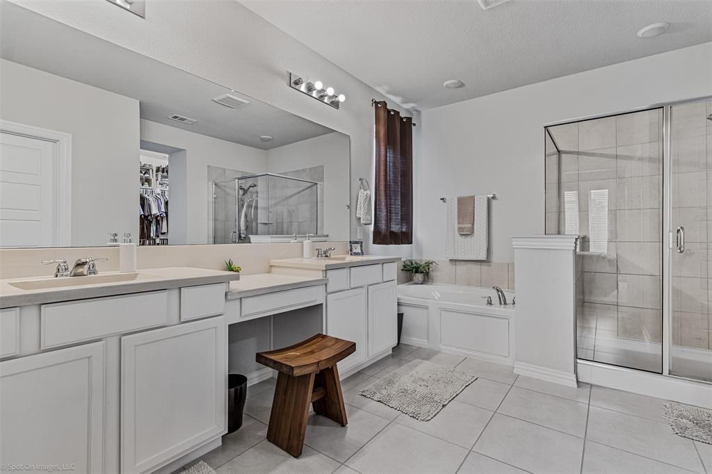 Full bathroom featuring double vanity, a shower stall, a garden tub, and tile patterned flooring