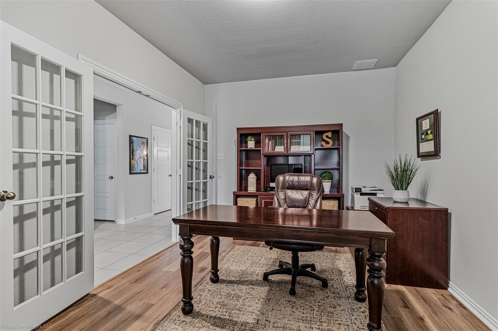 Home office with french doors, wood finished floors, and a textured ceiling
