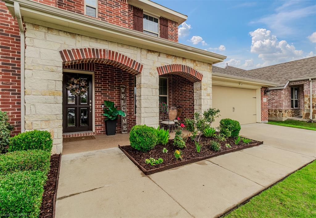Entrance to property with an attached garage, brick siding, concrete driveway, and stone siding Entrance to property with an attached garage, brick siding, concrete driveway, and stone siding