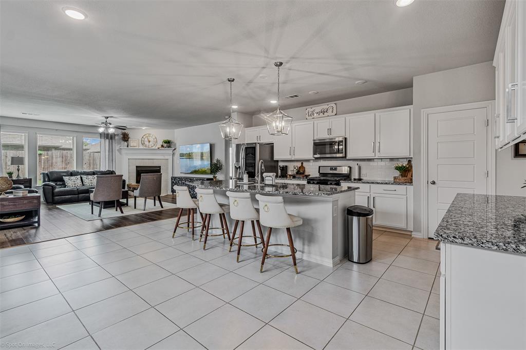 Kitchen with stainless steel appliances, a kitchen breakfast bar, a tiled fireplace, open floor plan, and white cabinets Kitchen with stainless steel appliances, a kitchen breakfast bar, a tiled fireplace, open floor plan, and white cabinets