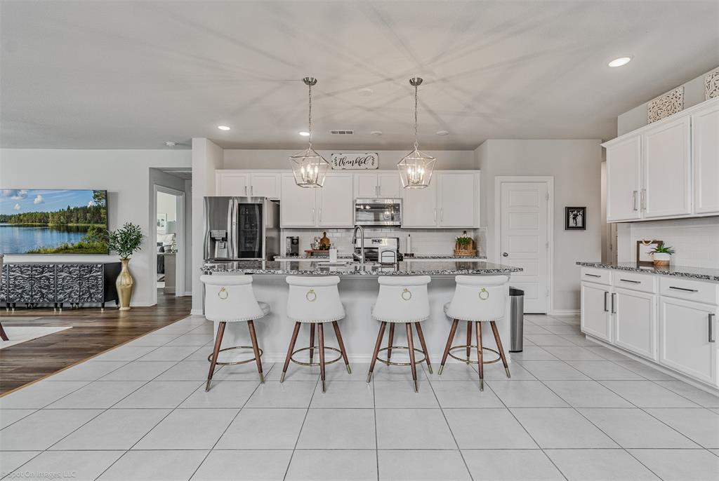 Kitchen featuring stainless steel appliances, decorative backsplash, a kitchen breakfast bar, recessed lighting, and white cabinets Kitchen featuring stainless steel appliances, decorative backsplash, a kitchen breakfast bar, recessed lighting, and white cabinets