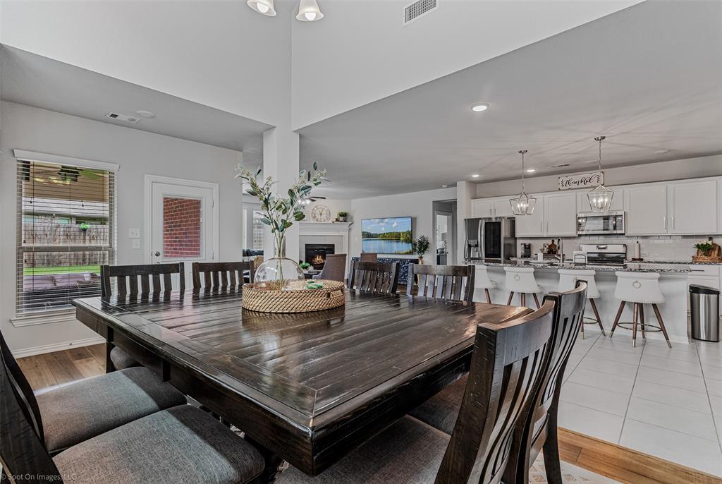Dining space featuring healthy amount of natural light, a warm lit fireplace, recessed lighting, a chandelier, and light wood-type flooring