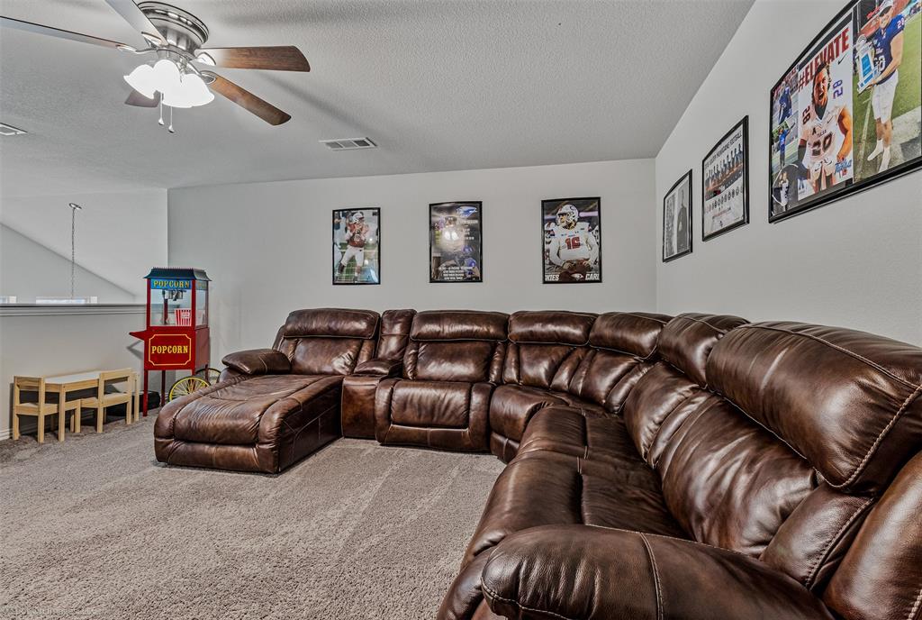 Carpeted living area featuring ceiling fan and a textured ceiling