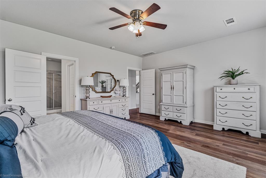 Bedroom featuring dark wood-type flooring, a ceiling fan, and ensuite bath