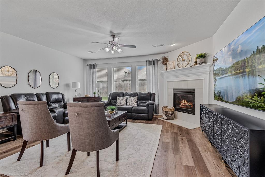 Living area with a fireplace, a ceiling fan, wood finished floors, and a textured ceiling Living area with a fireplace, a ceiling fan, wood finished floors, and a textured ceiling