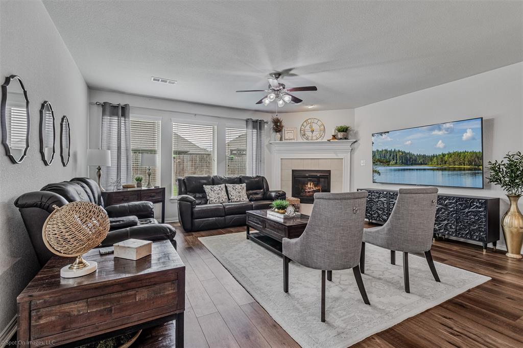 Living room with wood finished floors, a ceiling fan, a fireplace, and a textured ceiling Living room with wood finished floors, a ceiling fan, a fireplace, and a textured ceiling