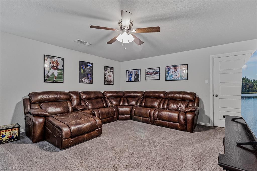 Carpeted living area featuring ceiling fan