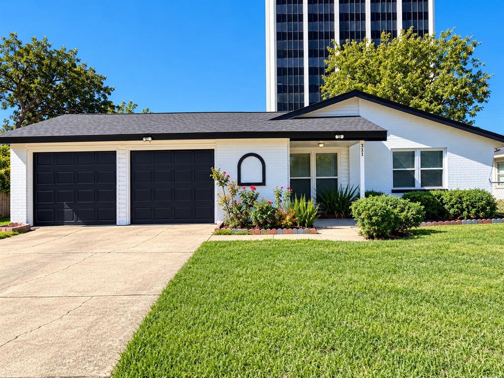 White brick exterior with dual-car garage, contrasting black trim, and gabled roofline
