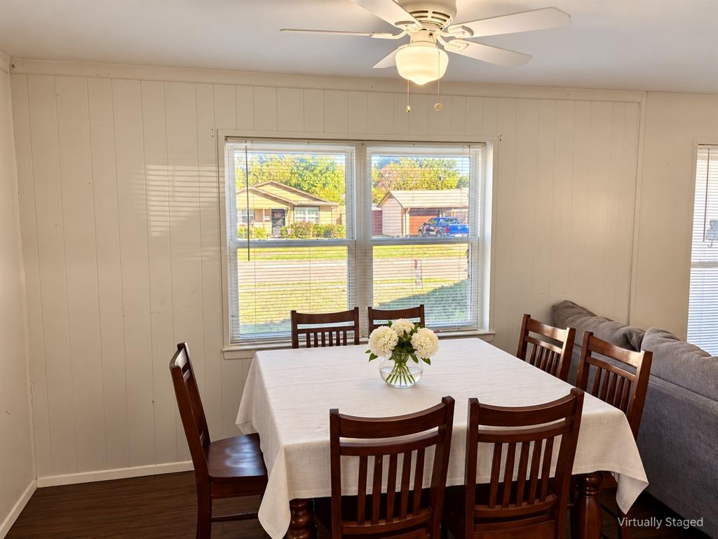 Interior space featuring wood-finish flooring, vertical paneling, double-pane windows, and a ceiling fan with integrated lighting