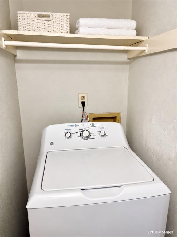 Laundry alcove featuring a top-load washer, a fixed upper storage shelf, and a white closet rod