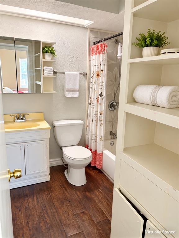 Bathroom featuring wood-finish flooring, built-in shelving unit, mirrored medicine cabinet, and a tub-shower combination with decorative wall tile