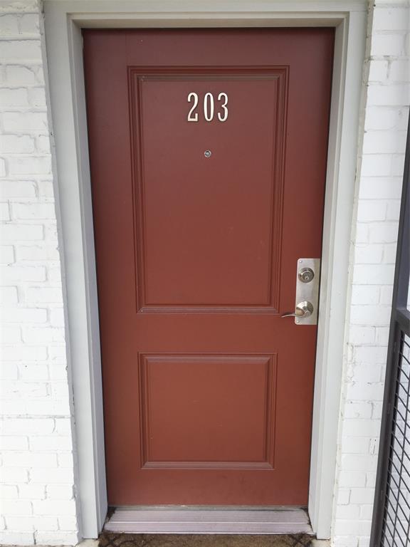 Solid-core two-panel entry door featuring a brushed metal lever handle, deadbolt, and integrated door viewer, set within a white painted brick exterior