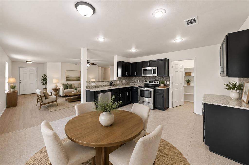 Kitchen featuring dark cabinetry, stone-surface countertops, tile backsplash, and stainless-steel appliances, with wood-finish flooring throughout