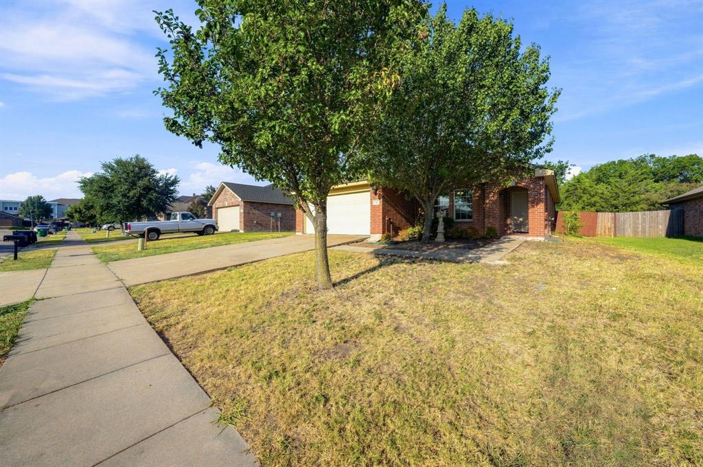Brick exterior residence featuring a front-facing attached two-car garage, concrete driveway, and mature landscaping