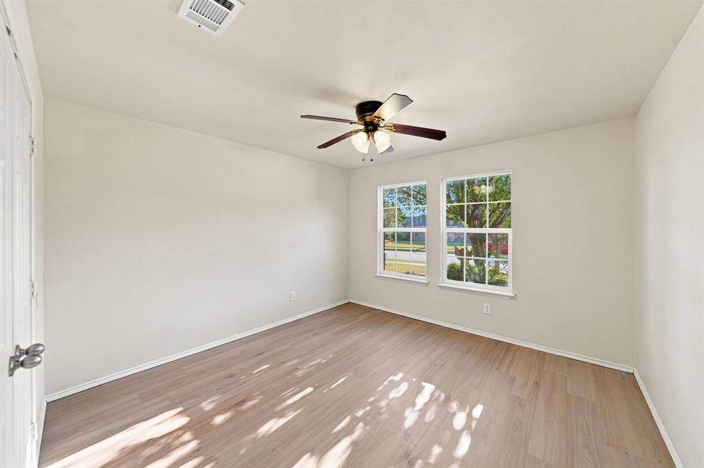 Interior space featuring wood-finish flooring, two dual-pane windows with grid mullions, and a central ceiling fan with integrated lighting