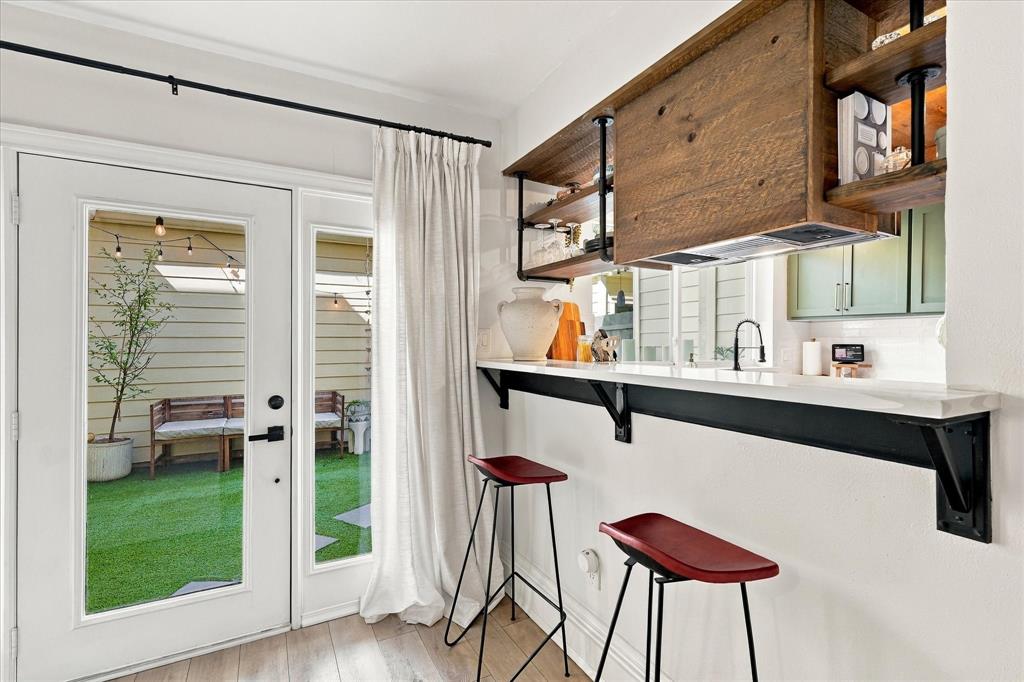 Built-in counter with industrial-style black brackets, wood-finish shelving with integrated plumbing-pipe accents, and glass-paneled exterior door