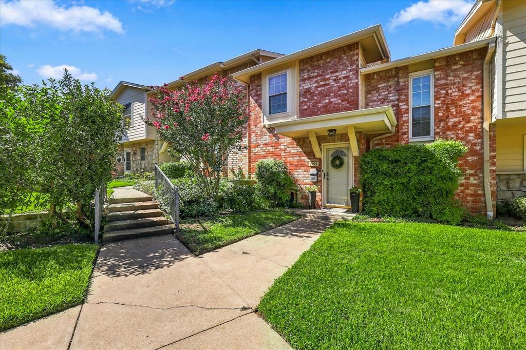 Multi-level exterior featuring red brick masonry, siding, concrete walkway, and landscaped grounds
