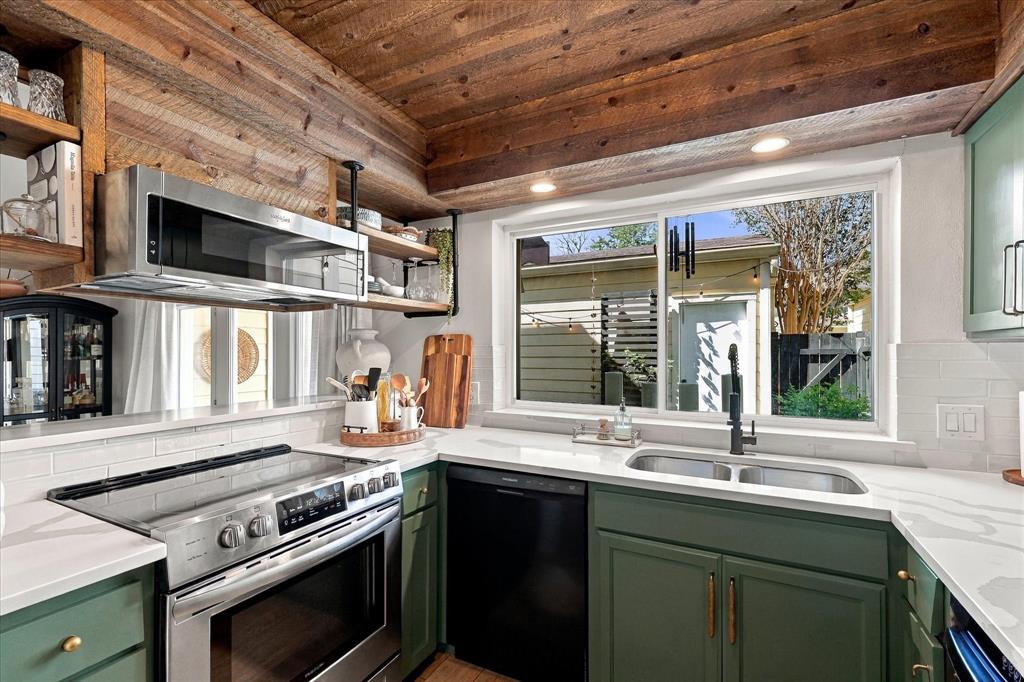 Kitchen featuring wood-paneled ceiling, white stone-finish countertops, subway tile backsplash, custom colored cabinetry, and stainless steel appliances