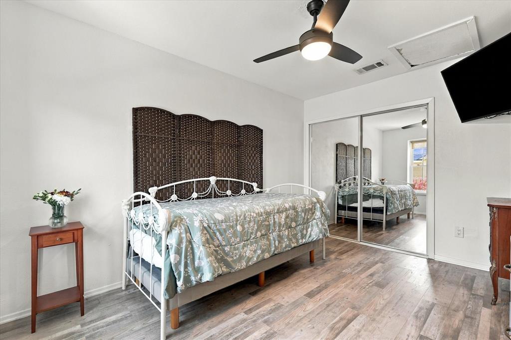 Wood-finish flooring, ceiling fan with integrated light, and sliding mirrored closet doors