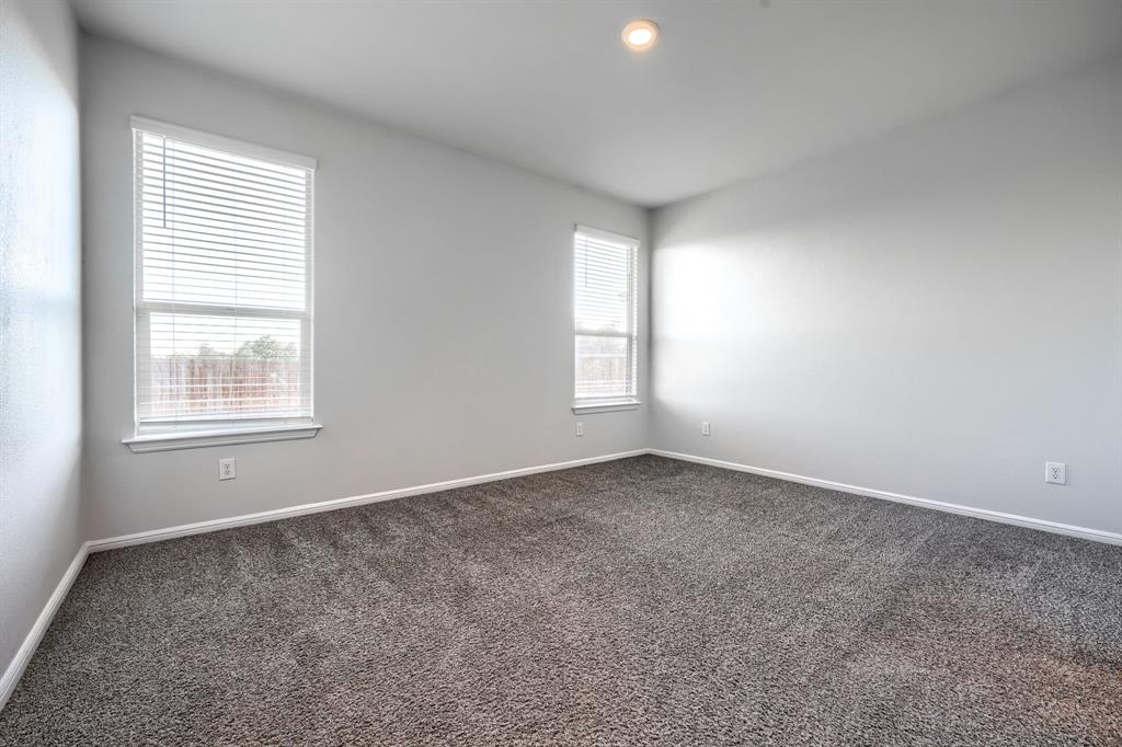 Neutral-toned interior space featuring neutral wall paint, wall-to-wall carpeting, two windows with horizontal blinds, and a recessed ceiling light