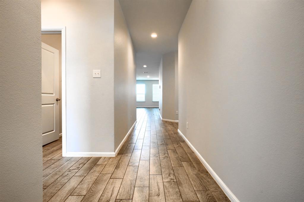 Hallway featuring wood-finish flooring, neutral walls, recessed lighting, and a multi-panel interior door