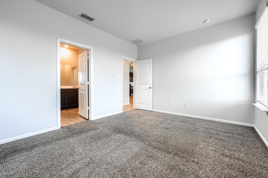 Neutral-toned interior space featuring textured wall-to-wall carpeting, crisp white interior doors, and horizontal slat window blinds