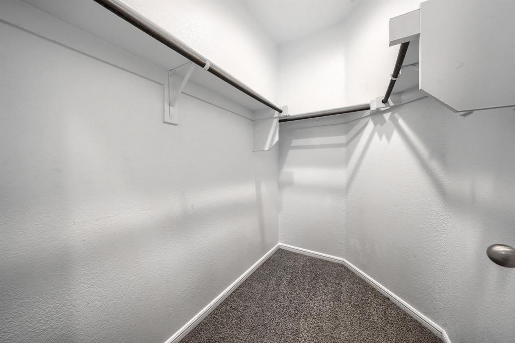 Storage area featuring wall-to-wall carpeting, tiered built-in shelving, and dual hanging rods