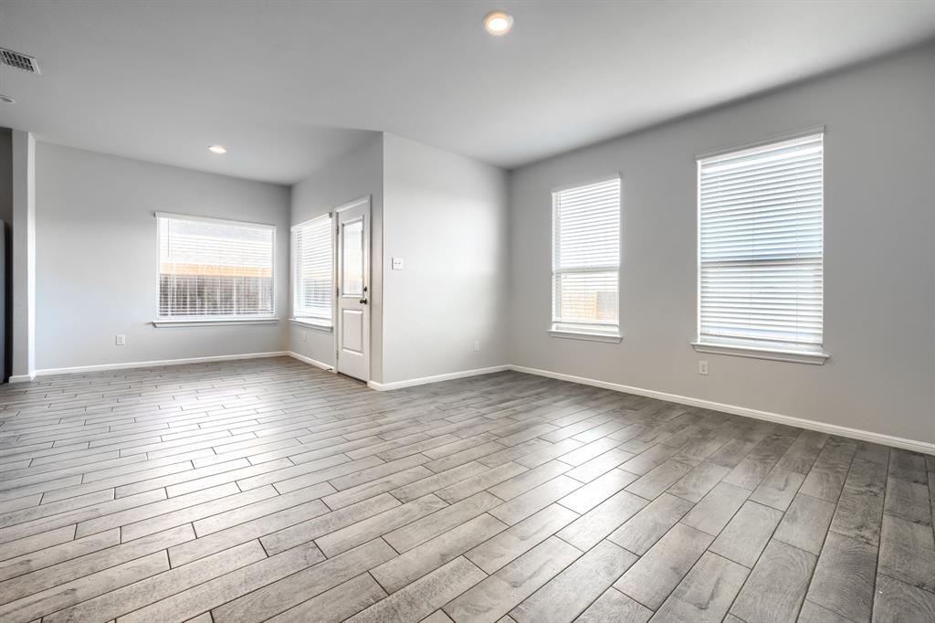 Neutral-toned interior featuring wood-finish flooring, recessed lighting, and multiple windows with installed blinds